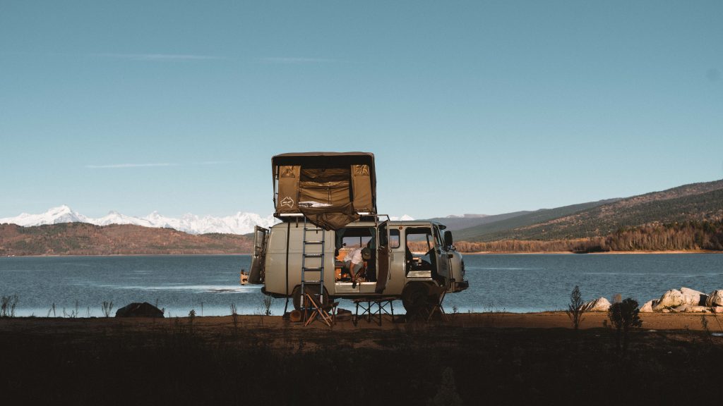 UAZ Camper with roof top tent in front of a lake